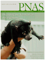 Cover of PNAS journal issue featuring Tasmanian Devil genome sequenced and a dark brown/black tasmanian devil being held in a hand